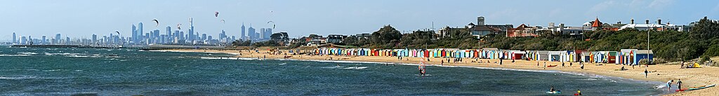 Brighton Bathing Boxes med Middle Brighton-piren och vågbrytaren och Melbournes stadssilhuett i bakgrunden. Foto: John O'Neill