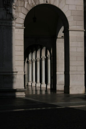 Sunlit Stone Archway – Poster – Ett elegant svartvitt fotografi av ett valvsystem med ståtliga pelare där ljus och skugga skapar ett dramatiskt och harmoniskt uttryck. De upprepade formerna ger motivet djup och tidlös karaktär.