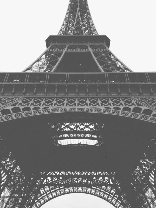 Paris Eiffel Tower - Poster. En kraftfull närbild i grodperspektiv av Eiffeltornet i Paris. Det svartvita fotografiet låter gråtonerna dominera