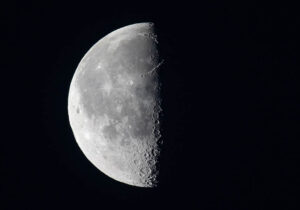 Månen – Poster – Ett stilrent svartvitt fotografi av en perfekt halvmåne där ljus och mörker möts i en skarp kontrast.